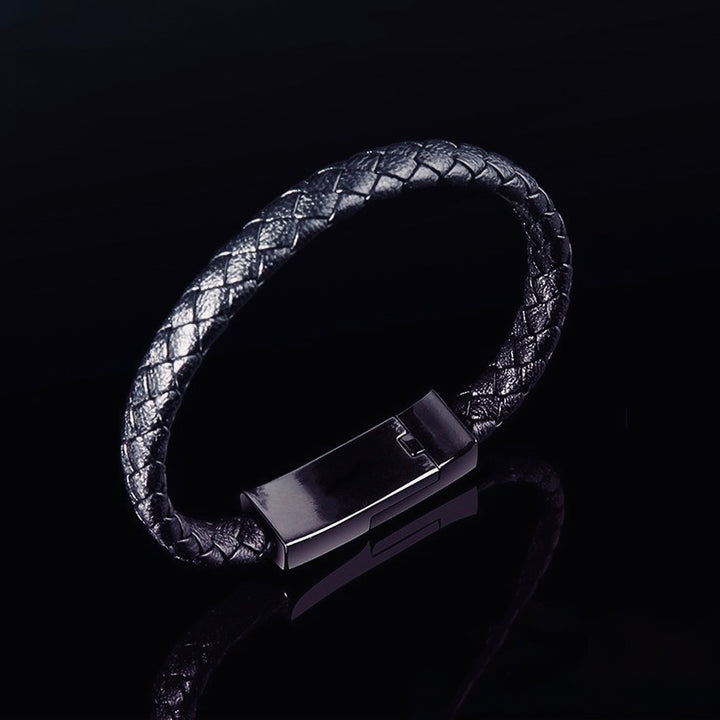 Black braided leather bracelet with a metallic clasp on a black background